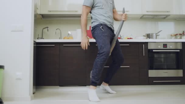 Κοντινά πλάνα άνθρωπος Καθαρισμός ποδιών δαπέδου με ηλεκτρική σκούπα στην κουζίνα. - Πλάνα, βίντεο