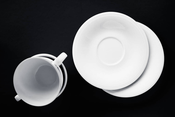 Bílé nádobí z černého nádobí, prázdný pohár na pozadí černé roviny - Fotografie, Obrázek