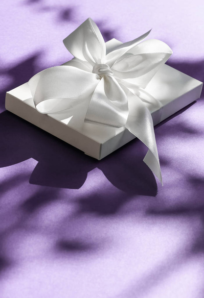 Luxus Urlaub weiße Geschenkschachtel mit Seidenband und Schleife auf violett - Foto, Bild
