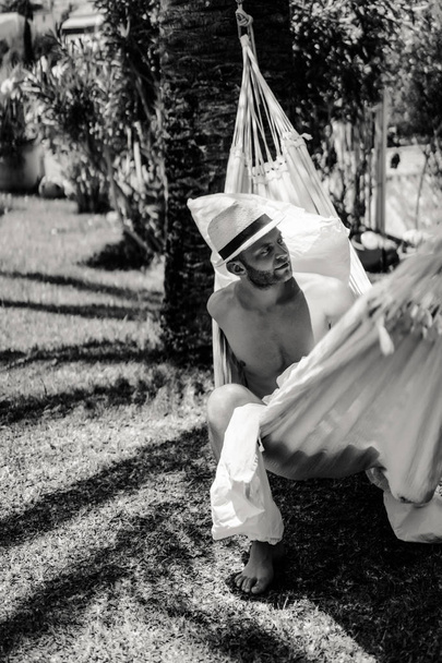 nude male relaxing in a hammock in the garden. - Foto, Bild