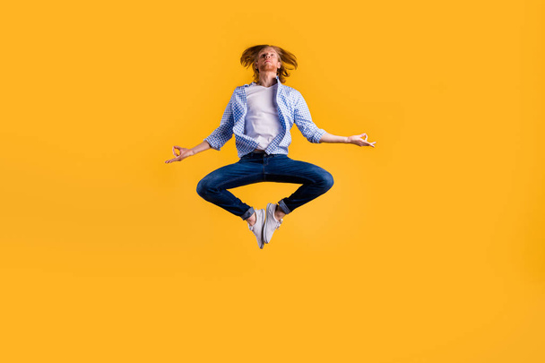 Full size photo of redhead guy jumping high meditating exercise holding body in lotus position wear casual trendy outfit isolated yellow background - Фото, зображення
