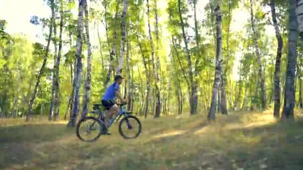 Young man biking on a forest road in a sammer day - Záběry, video