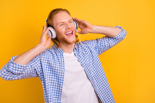 Photo of cheerful cute handsome screaming guy wearing headphones shouting words and lines of his favorite song dreaming isolated over vibrant color background - Valokuva, kuva