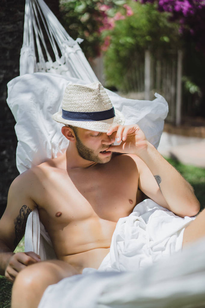 nude male relaxing in a hammock in the garden. - Фото, зображення