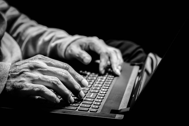 close up BW old man hands surfing internet on laptop computer. old people and technology concept - Foto, Bild