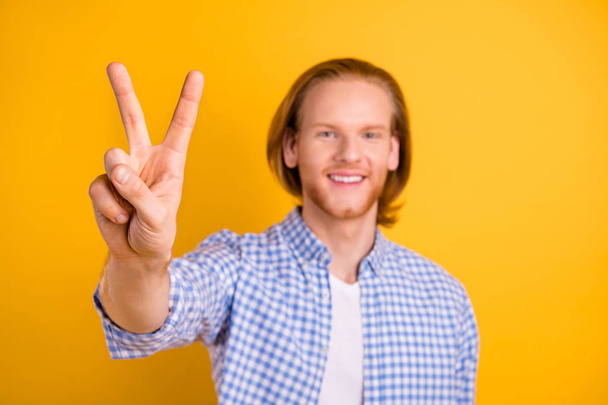 Photo of handsome cheerful guy greeting you by showing v-sign smiling toothily wearing blue shirt isolated vivid color background - Foto, afbeelding