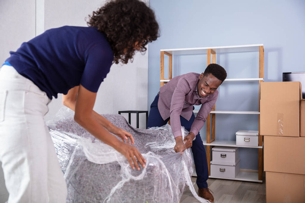Young African Couple Unpacking Their New Sofa - Zdjęcie, obraz