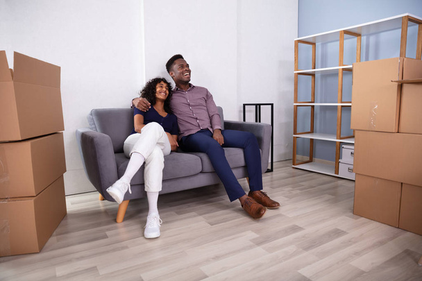 Young Couple Sitting On Couch Inside Their New Home - Photo, Image
