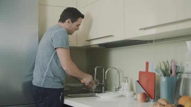 Alegre esposo haciendo tareas domésticas. persona sonriente lavado de vidrio
 - Imágenes, Vídeo