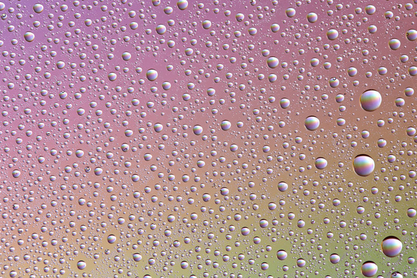 Gotas em vidro de diferentes tamanhos e cores em um fundo colorido, textura
 - Foto, Imagem