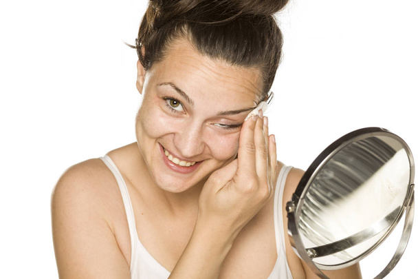 mladá šťastná žena jí čistí obličej s bavlněnou destiček na bílém pozadí - Fotografie, Obrázek