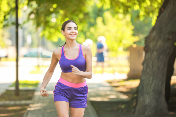 Sporty young woman running in park - Foto, imagen