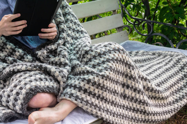 gambe di ragazza sotto caldo plaid di lana lavorato a maglia. Ragazze sedute sul
  - Foto, immagini