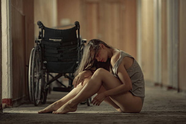Eine geschlagene Frau, die Opfer von Gewalt wurde, sitzt auf einem Krankenhausflur. - Foto, Bild