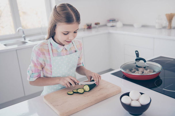 Close-up portrait of her she nice attractive beautiful charming cute pre-teen girl chopping fresh useful healthy green eco vegan vegs salad in light white interior room kitchen house indoors - Photo, image