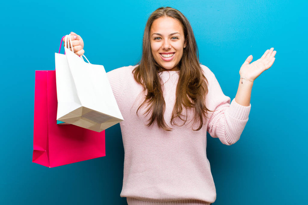 young woman with shopping bags against blue background - Foto, Bild