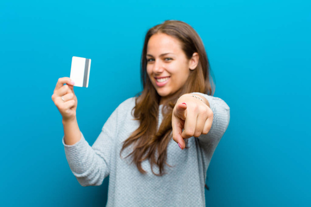 young woman with a credit card against blue background - Fotografie, Obrázek