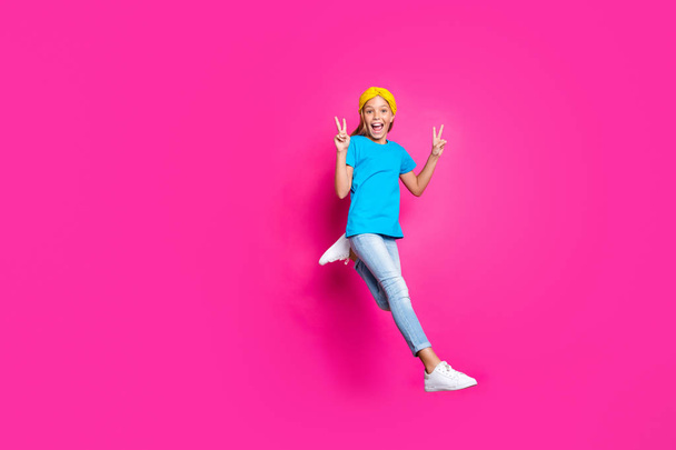 Full body photo of funny funky rejoicing blonde haired kid have fun jump run after discounts make v-signs wear denim jeans blue yellow outfit sneakers isolated over pink color background - Фото, изображение