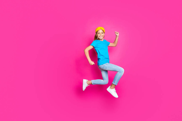 Full size photo of positive cheerful kid jump run have fun enjoy spring holiday discounts wear blue denim jeans clothes sneakers isolated over pink color background - Фото, изображение