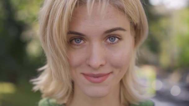 Attractive caucasian woman with medium length haircut looking at camera. Portrait of a beautiful blonde grey-eyed girl. - Felvétel, videó