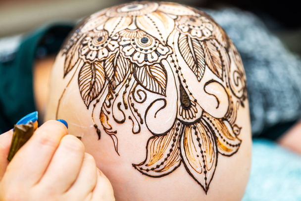 Tekening proces van henna Mehndi ornament op Womans hoofd - Foto, afbeelding