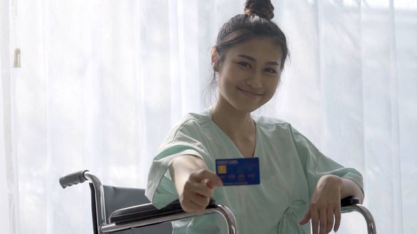 Happy patient hold credit card and smile while sitting on wheelc - Photo, Image