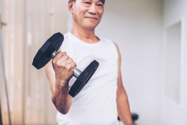 Hombre mayor levantando mancuerna en gimnasio de fitness
. - Foto, imagen