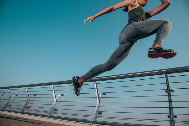 Cropped photo of a sportswoman in motion next to the banister outdoors. Website banner - Фото, зображення