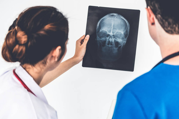 Врачи, работающие с рентгеновской пленкой головы пациента
. - Фото, изображение