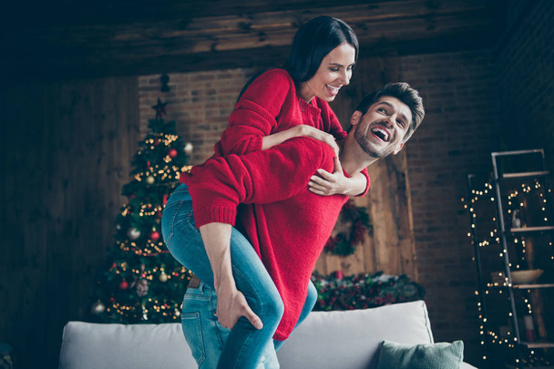 Profile side photo of two people romantic man holding piggyback his wife enjoy new year christmas party x-mas holidays in house with illumination lights noel decoration indoors - Valokuva, kuva