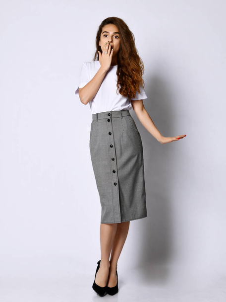 Young beautiful woman posing in new white bluesque and gray skirt on high heels full body on a white background - Valokuva, kuva