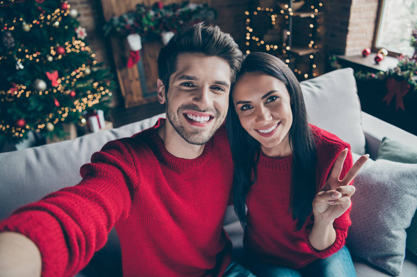 Top above angle photo of two people romantic guy and lady make v-signs selfie have christmas vacation x-mas holidays sit on divan in house with newyear decoration illlumination indoors - Fotó, kép