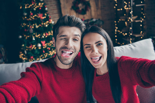 Close up photo of two funky crazy romantic people making selfie fooling on christmas x-mas vacation sitting on divan in decorative house with newyear illumination indoors - Фото, зображення