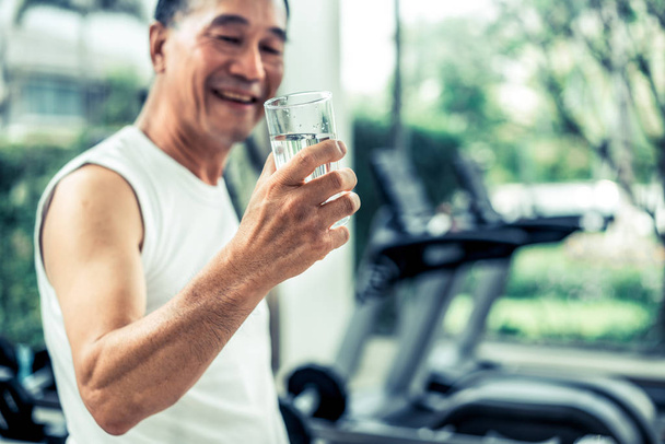 Hombre mayor beber agua mineral en el gimnasio
. - Foto, imagen