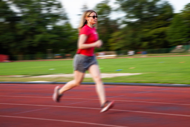 desenfoque movimiento de la mujer joven en pista de atletismo al aire libre
 - Foto, Imagen