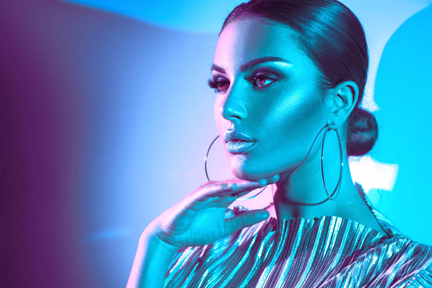 Fashion model brunette woman in colorful bright neon lights posing in studio. Trendy glowing makeup, metallic silver lips. - Zdjęcie, obraz