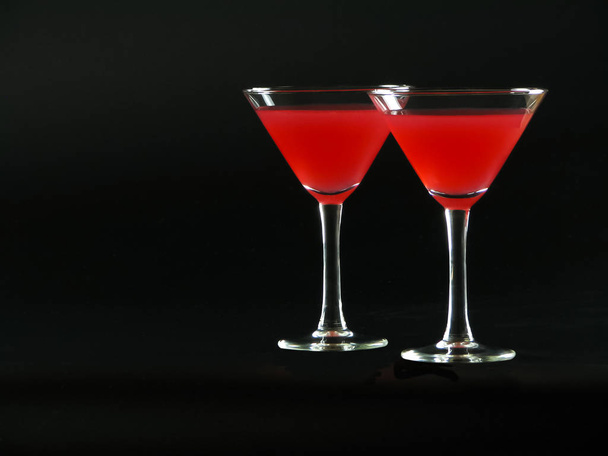 Яскраво-червоний коктейль "Бакарді" у двох коктейльних келихах на чорному спині
 - Фото, зображення