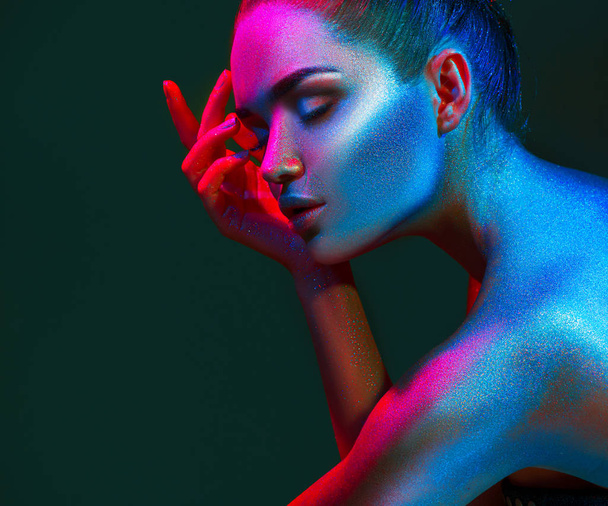 Fashion model woman in colorful bright sparkles and neon lights posing in studio. Art design colorful vivid makeup. - Valokuva, kuva