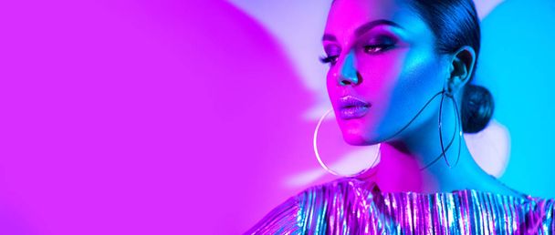 Fashion model brunette woman in colorful bright neon lights posing in studio. Trendy glowing makeup, metallic silver lips. - Fotografie, Obrázek