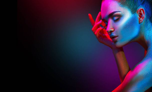 Fashion model woman in colorful bright sparkles and neon lights posing in studio. Art design colorful vivid makeup. - 写真・画像
