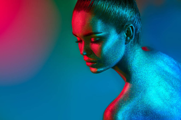 Fashion model woman in colorful bright sparkles and neon lights posing in studio. Art design colorful vivid makeup. - Foto, afbeelding