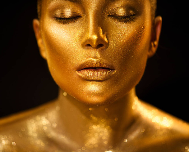 Golden skin woman portrait closeup. Sexy female model with holiday golden shiny professional makeup. Golden metallic body. - Foto, afbeelding