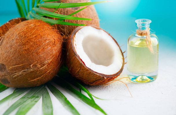 Aceite de coco en una botella con coco y hoja de palmera verde o
 - Foto, imagen