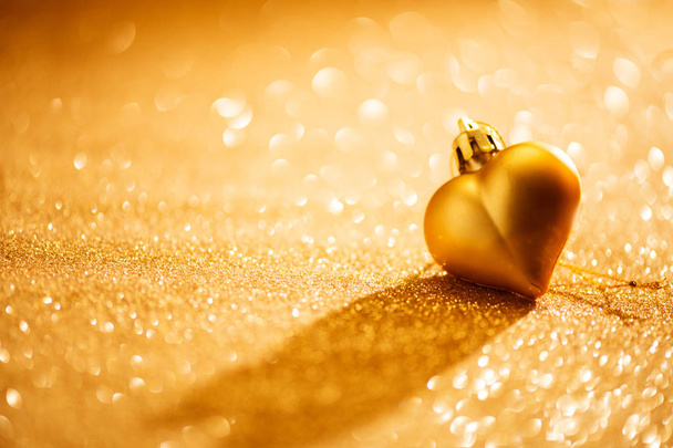 Valentine's Day holiday background. Heart shape bauble over golden background - Valokuva, kuva