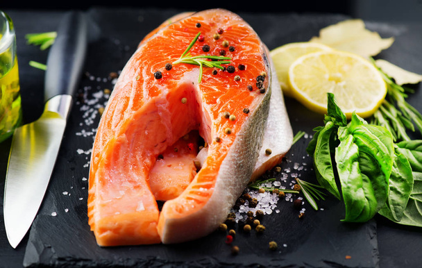 Salmon. Raw trout fish steak with herbs and lemon on black slate - Foto, Imagem