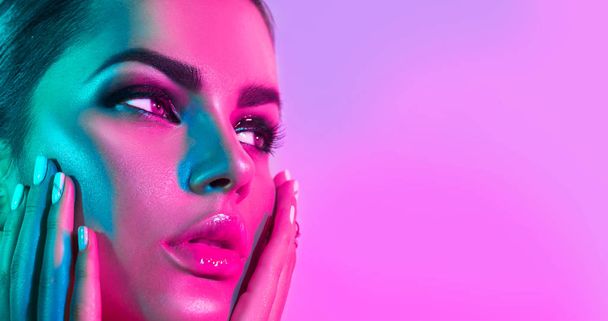 Fashion model woman in colorful bright lights with trendy makeup posing in studio - Fotografie, Obrázek