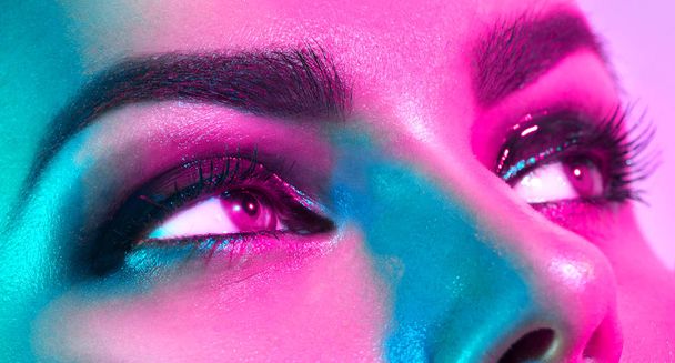 Fashion model woman in colorful bright lights with trendy makeup posing in studio - Foto, imagen