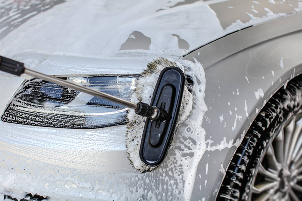 Frontlicht von silbernem Auto mit Bürste in Selbstbedienungswagen gewaschen - Foto, Bild