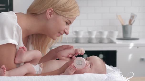 la madre premurosa dà per bere acqua dalla bottiglia alla sua neonata sul fasciatoio sulla cucina poi bacia le mani del piccolo bambino
 - Filmati, video