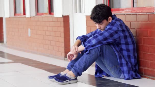 Nagranie znęcanego chłopca siedzącego na podłodze w szkole średniej - Materiał filmowy, wideo